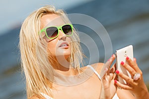 Girl on beach with phone.