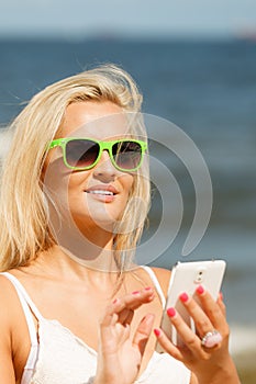 Girl on beach with phone.