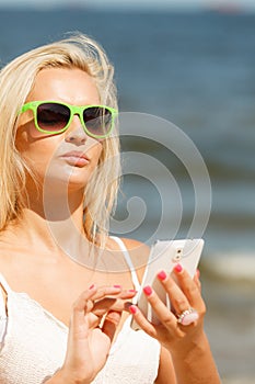 Girl on beach with phone.