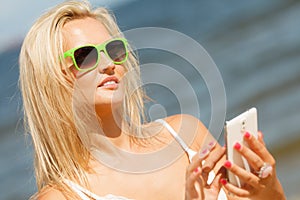 Girl on beach with phone.