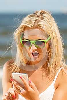 Girl on beach with phone.