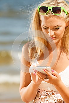 Girl on beach with phone.