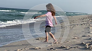 A girl is on the beach shose having fun with the waves coming in