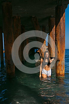 Girl on the beach with wet hair, beautiful figure and clean skin against the sea in sunny weather