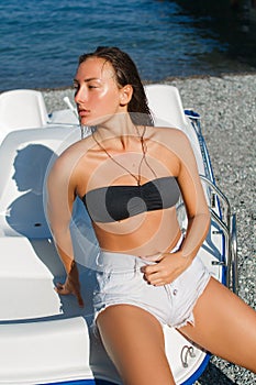 Girl on the beach with wet hair, beautiful figure and clean skin against the sea in sunny weather