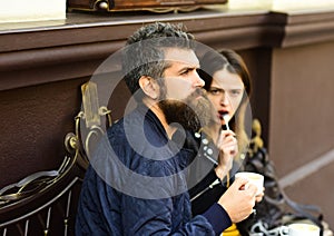 Girl and bearded guy have coffee on brown background