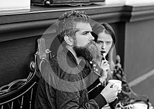 Girl and bearded guy have coffee on brown background