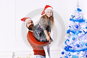 Girl and bearded man with happy faces near Christmas tree