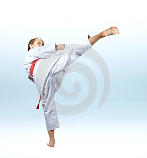 Girl beats a high kick leg on the light background