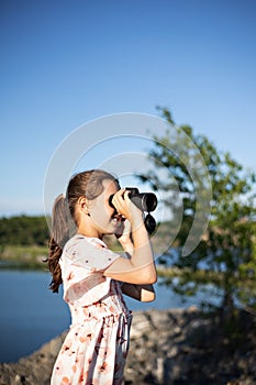 a girl in a beautiful dress stands on the top of a mountain holding binoculars