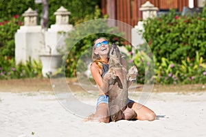 The girl beautiful in jeans shorts and an undershirt also gatsya with dogs, game with dogs on the beach.