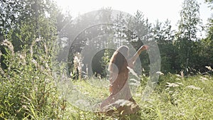 A girl in a beautiful long dress is spinning in the rays of sunlight in the forest. Summer mood. The mood of freedom. A romantic