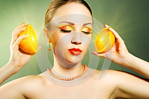 Girl with beautiful make-up holding orange fruit
