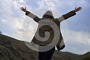 Girl on beautiful mountain view feeling free with wind and sky. Isolated woman on nature background, freedom, post apocalyps