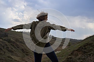 Girl on beautiful mountain view feeling free with wind and sky. Isolated woman on nature background, freedom, post apocalyps