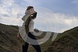 Girl on beautiful mountain view feeling free with wind and sky.  woman on nature background, freedom, post apocalyps