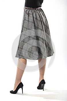 girl with beautiful slender legs in a long wool skirt on a white background, long gray plaid skirt