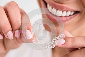 Girl with a beautiful smile holding a transparent mouth guard photo