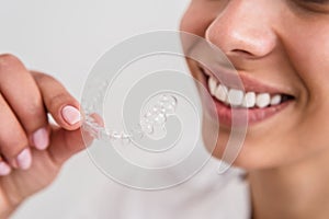 Girl with a beautiful smile holding a transparent mouth guard photo