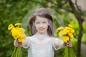 Girl in a beautiful white dress poses with yellow dandelion flowers