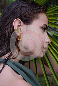 Girl beauty face on palm leaves. Summer portrait of beautiful young woman. Summer vacation. Beautiful sensual woman
