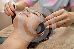 girl in a beauty salon doing a wonderful facial massage with stones to increase lymph flow.