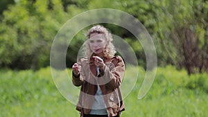 A girl beckons her boyfriend standing on a beautiful meadow.