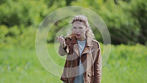 A girl beckons her boyfriend standing on a beautiful meadow.