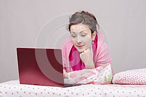 Girl in bed with interest works for laptop