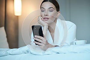 The girl  in bed. She looks at the smartphone. Influence of social networks on youth
