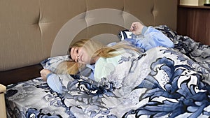 Girl in bed in the morning in blue pajamas