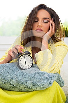 Girl in bed in morning with retro clock