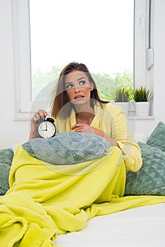 Girl in bed in morning with retro clock