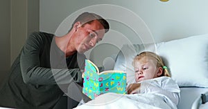 Girl on bed reading book with her father