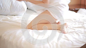 Girl on the bed to put a cream on legs. beautiful woman skin care