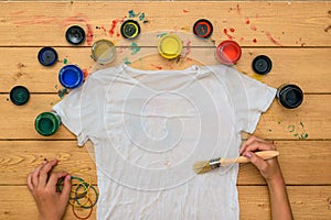 The girl begins to paint a white t-shirt in the style of tie dye.