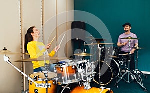 The girl behind the drum kit laughs. Music lesson with teacher.
