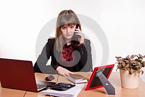 The girl behind office table talks on phone