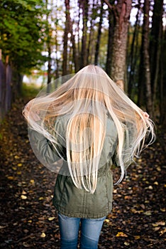 Girl from behind outside waiving her long blonde hair photo