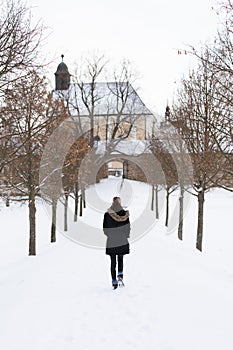 Girl from behind on the snowy winter path going to church