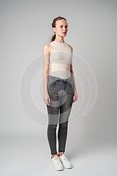 Girl in Beige Tank Top and Grey Jeans on gray background