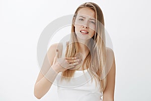 Girl being offended and hurt standing displeased and insulted frowning poking herself in chest being deeply shocked photo