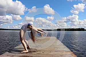 Girl bending over backwards into a backbend at a lake in Finland