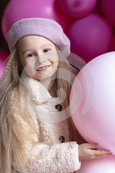 Girl in beret playing with pink, purple balloons, hildrens emotions. beautiful child on holiday. Kid birthday party concept