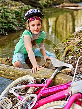 Girl on bicycle fording throught water onto log in park.