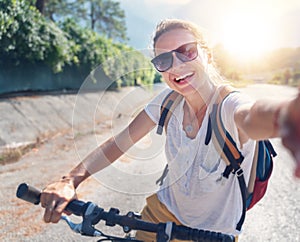 Girl with a bicycle makes selfie on a smartphone. Summer vacation and travel by bicycle, sports and outdoor activities