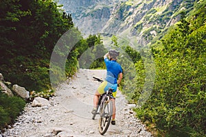 Girl on a Bicycle travels to Slovakia. black helmet, blue shirt, mountains, high Tatras,