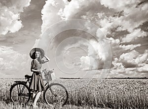 Girl with bicycle on wheat field