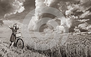 Girl with bicycle on wheat field.