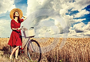 Girl with bicycle on wheat field.